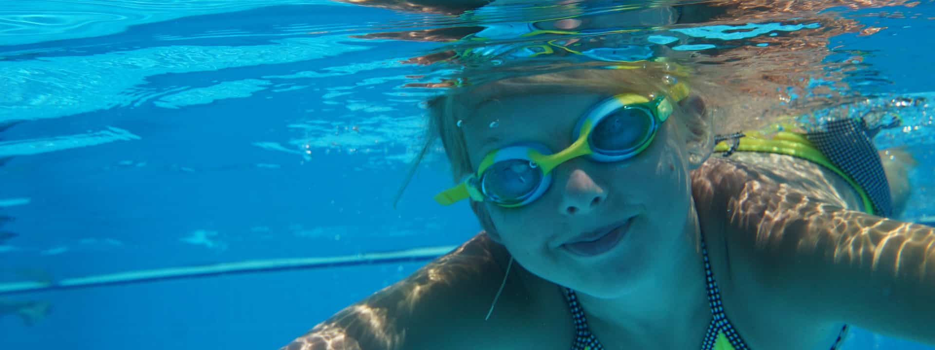 enfant-nage-dans-une-piscine-avec-bonnet-et-lunettes